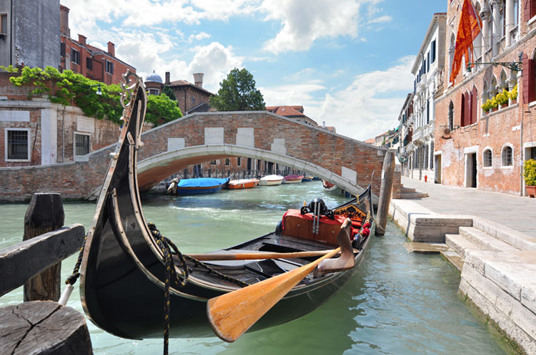 Venetian bridge over a canal with a gondola moored at the side.
