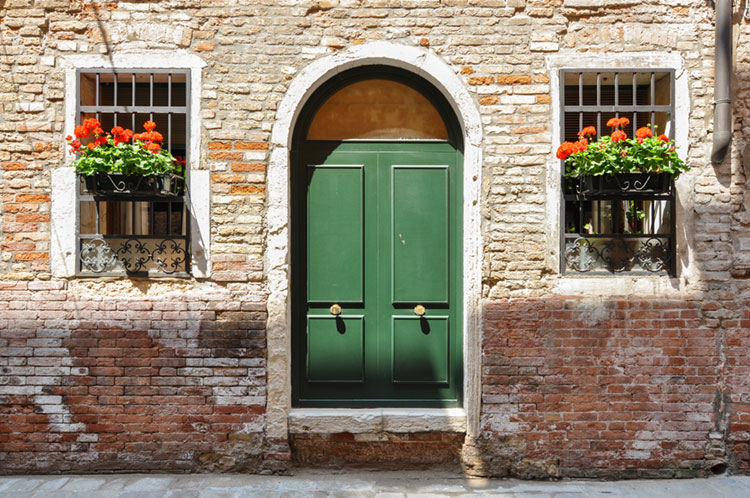 Geranium flower boxes and green doors on a cute home in Venice.