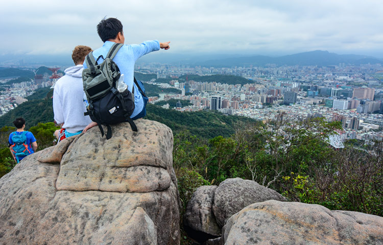 Young foreign student and Taiwanese man on a mountain overlooking Taipei.